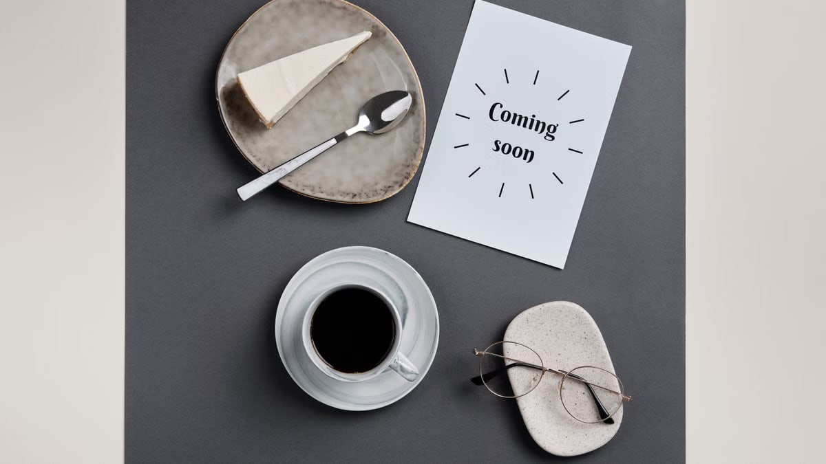 Stylish flatlay featuring coffee, slice of cheesecake, and eyeglasses on paper.